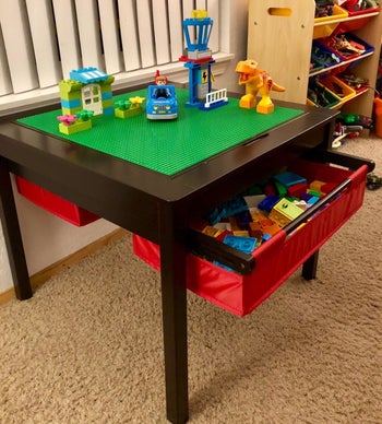 reviewer's photo of their child's Lego creations on the table and the remaining pieces in the red storage bin