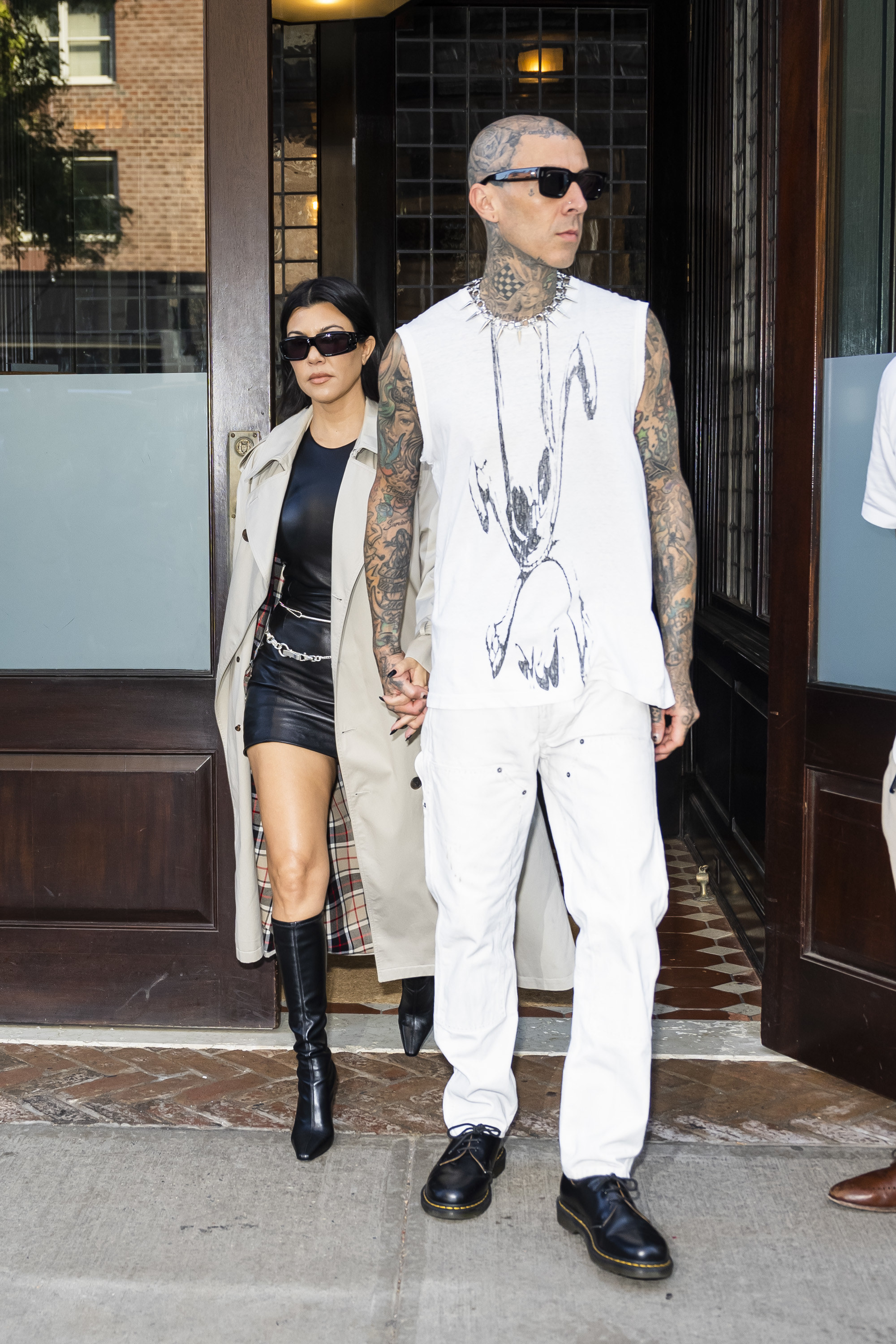 Travis holds Kourtney&#x27;s hand while walking out of a building