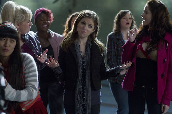 Anna Kendrick stands in a group of women singing a capella
