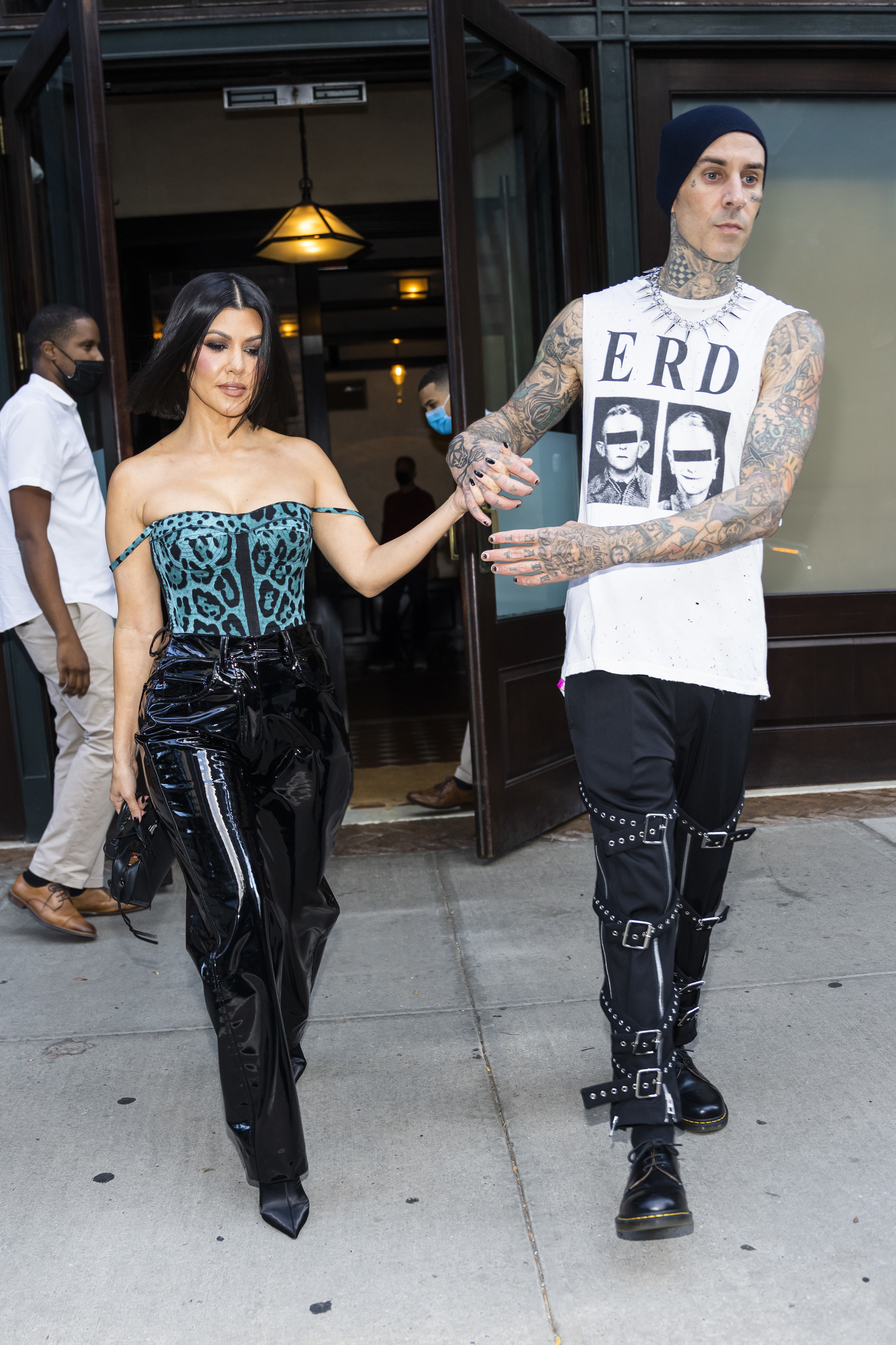 Travis holds Kourtney&#x27;s hand while walking out of a building with her