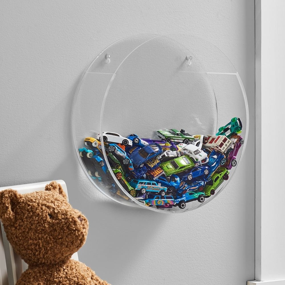 Toy cars displayed in a clear acrylic holder hanging from a wall