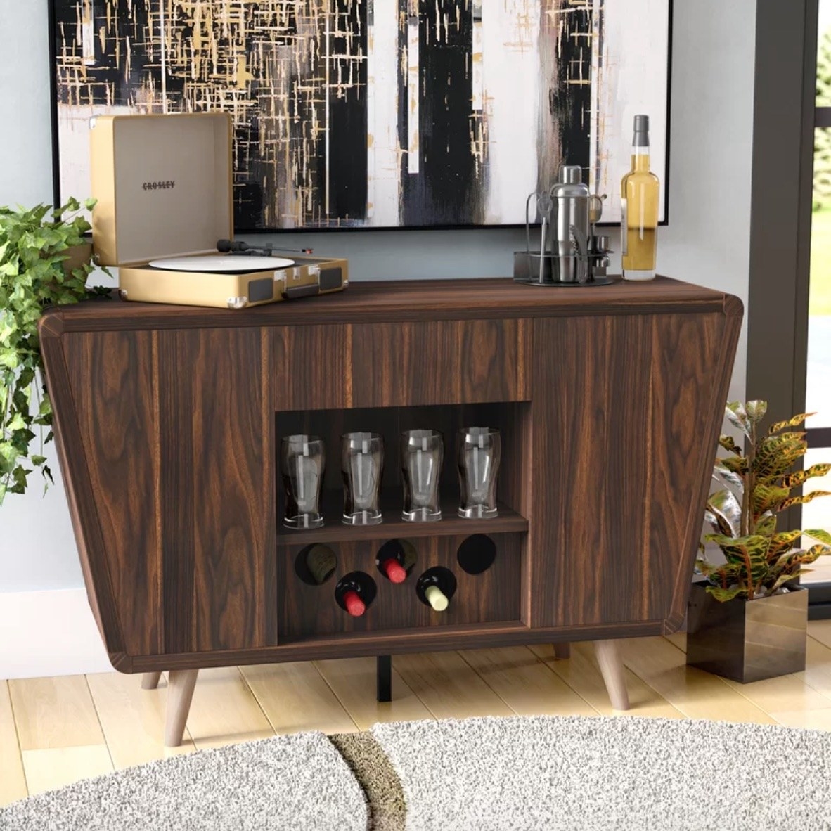 a dark brown wooden asymmetrical side board staged with bottles of wine, a cocktail making kick, an a record player