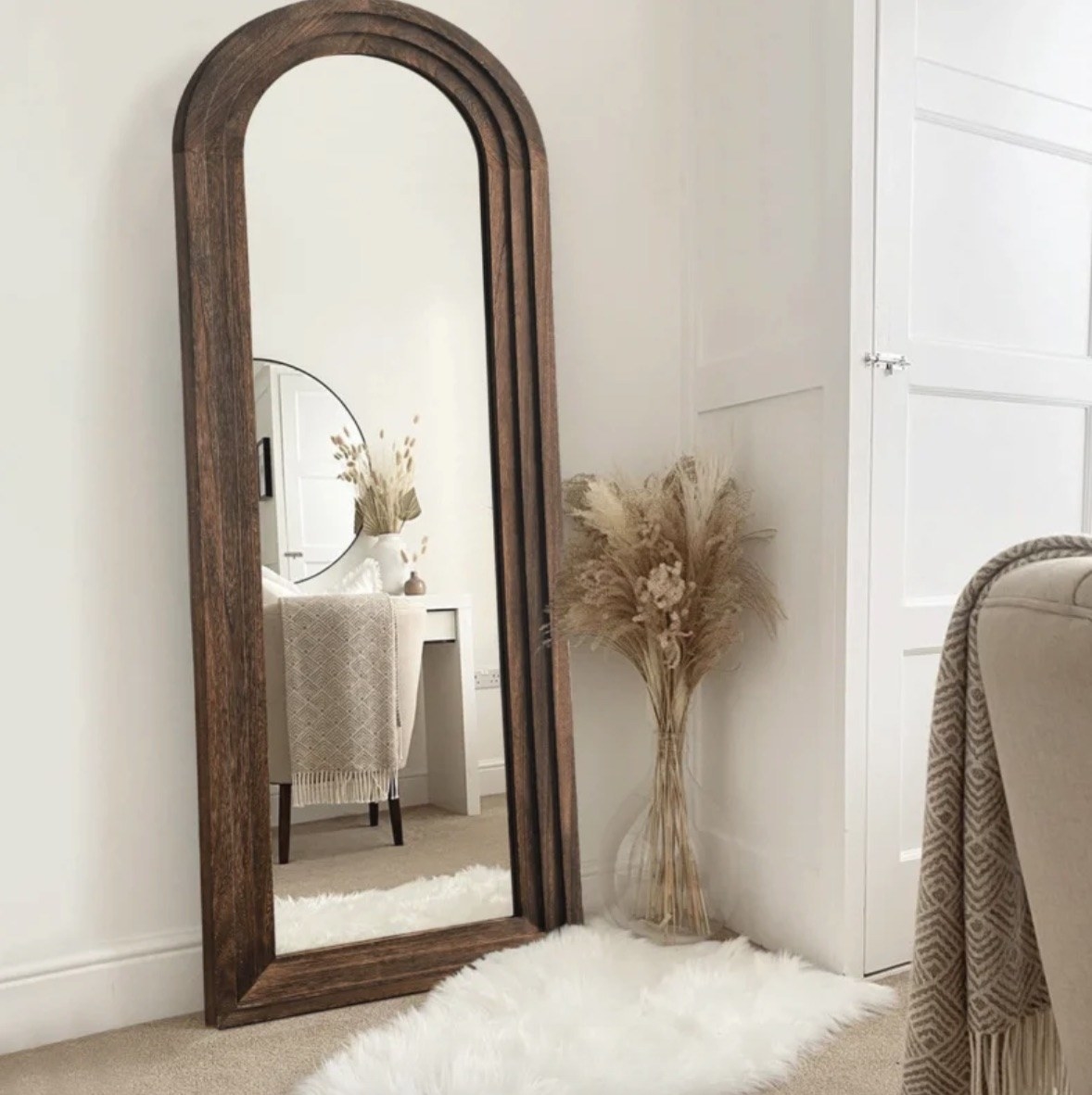 a floor mirror that&#x27;s rounded at the top and framed in dark wood