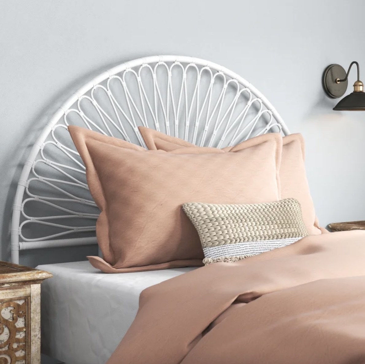 a white semi-circular rattan headboard behind a made bed