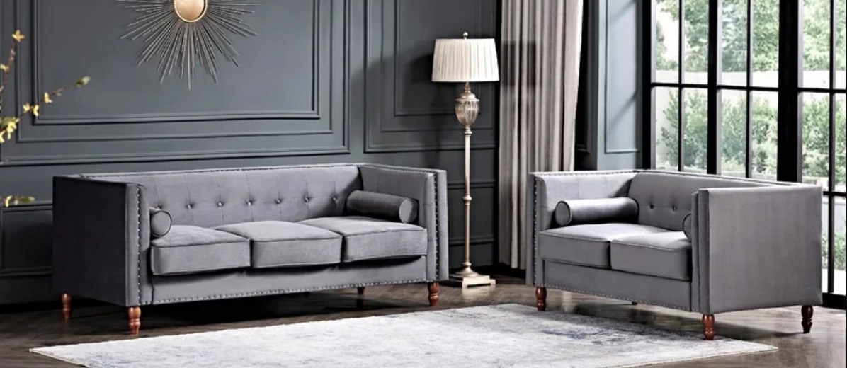 two grey velvet couches in a staged living room with a floor lamp in between them