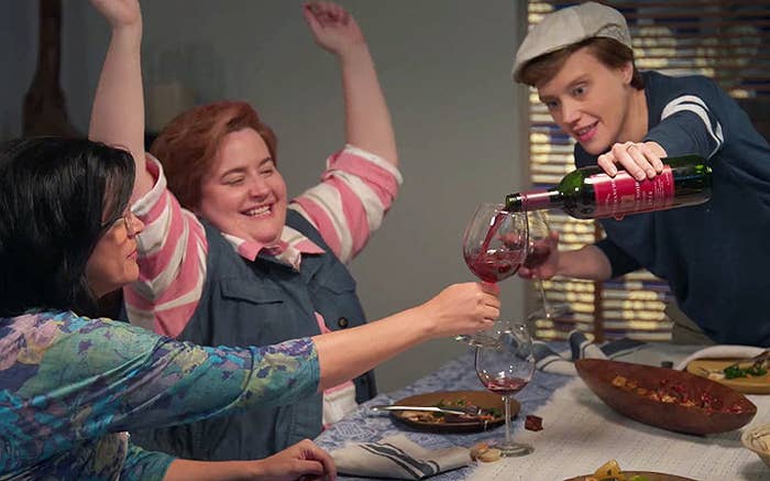 Kate McKinnon pours wine into a glass which Aidy Bryant cheers