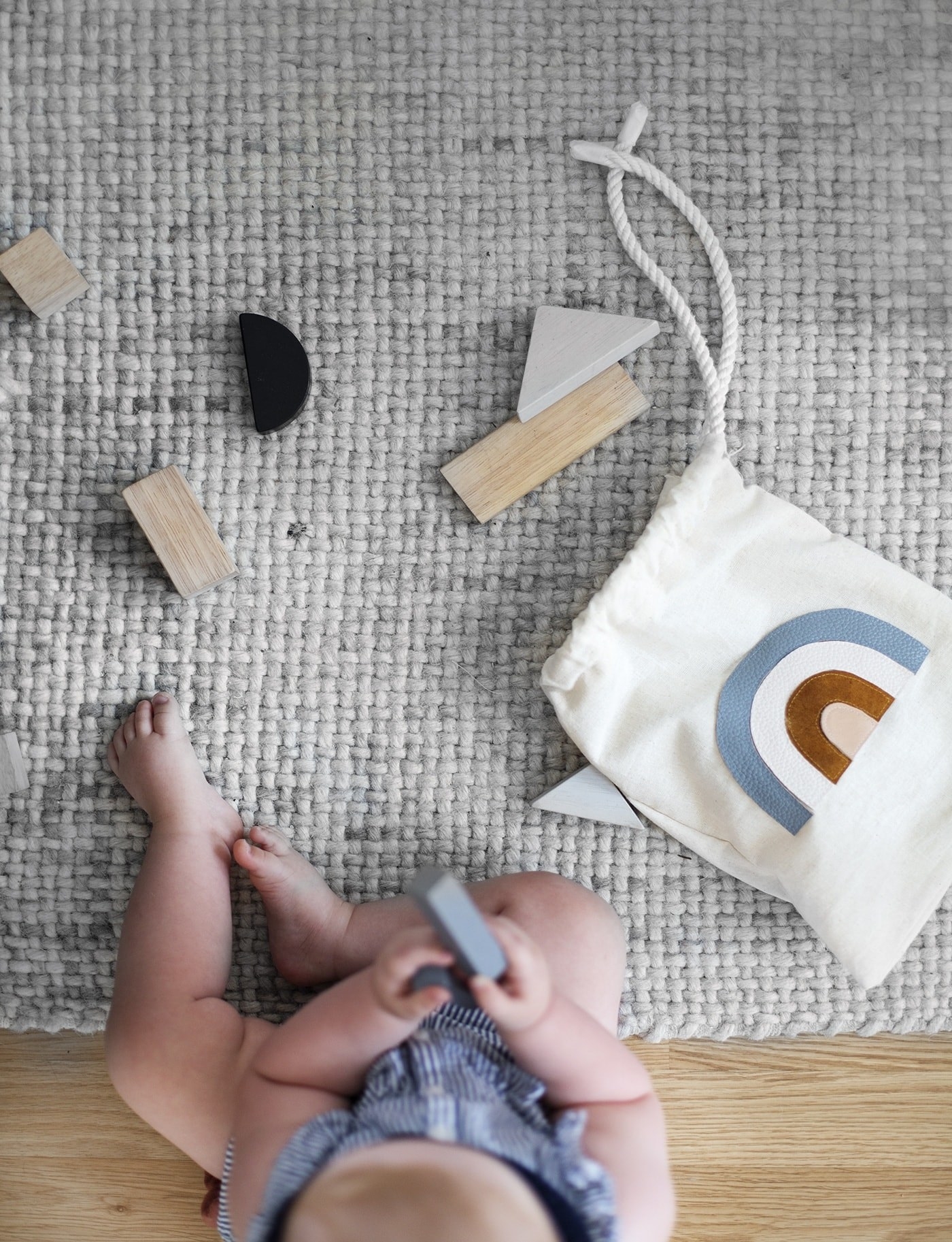 Blogger&#x27;s photo of a child playing with wooden toys with a rainbow bag lying on the rug next to them
