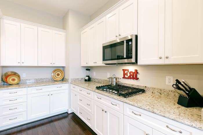 large kitchen with countertop stove top and a sign that says &quot;eat&quot;