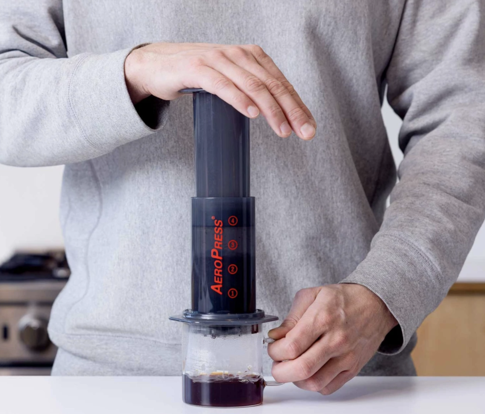 A person using an AeroPress to make a cup of coffee in the kitchen