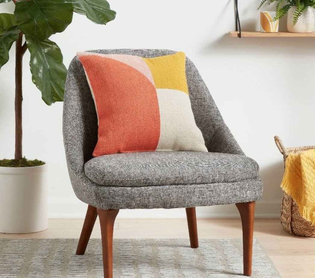 the pink, coral and yellow pillow on a gray chair
