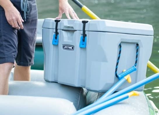 grey plastic cooler with rope handles on a boat