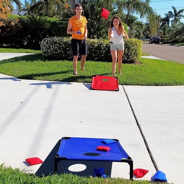 models playing with the blue and red PVC and fabric cornhole boards and beanbags