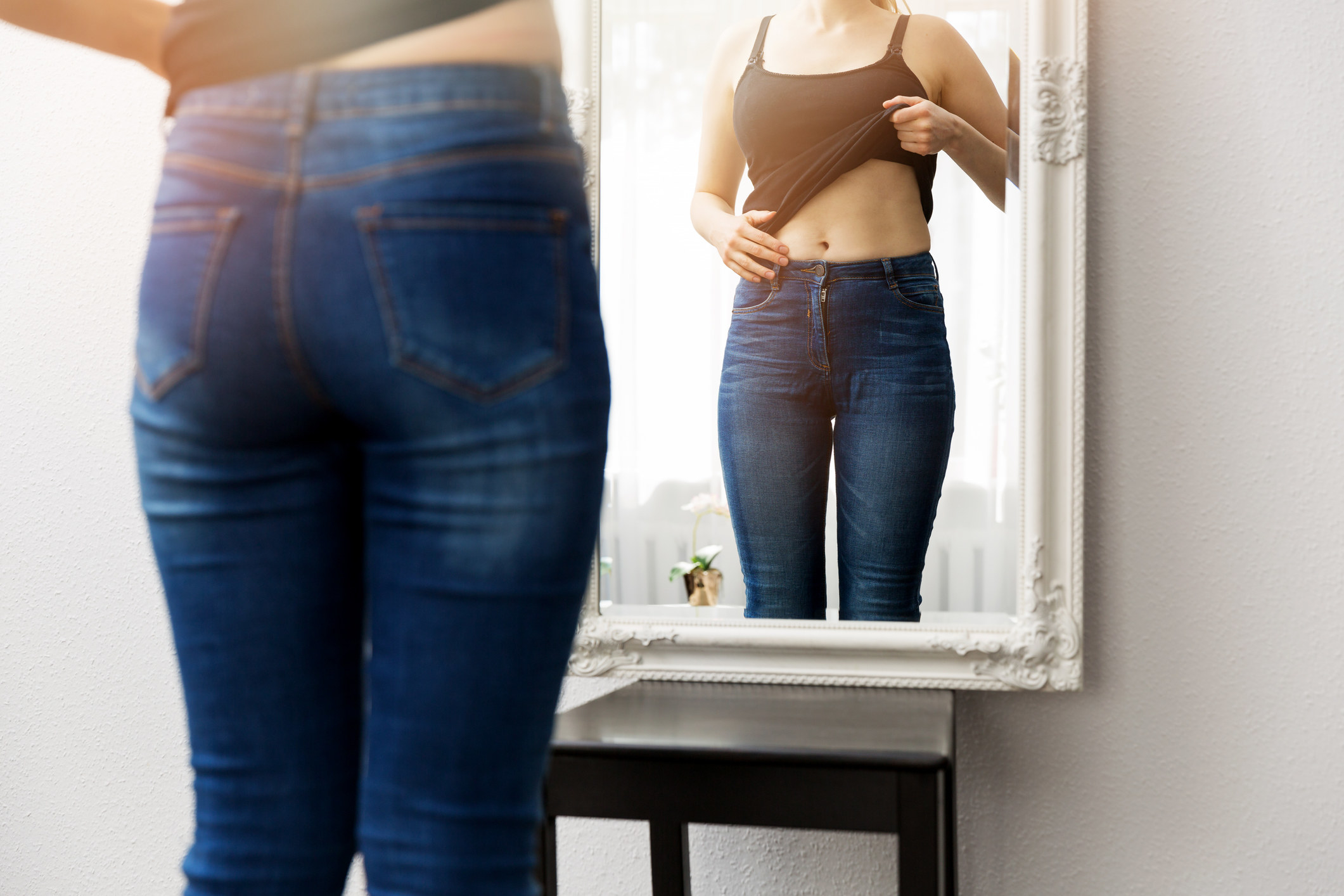 a woman looking at her stomach in a mirror