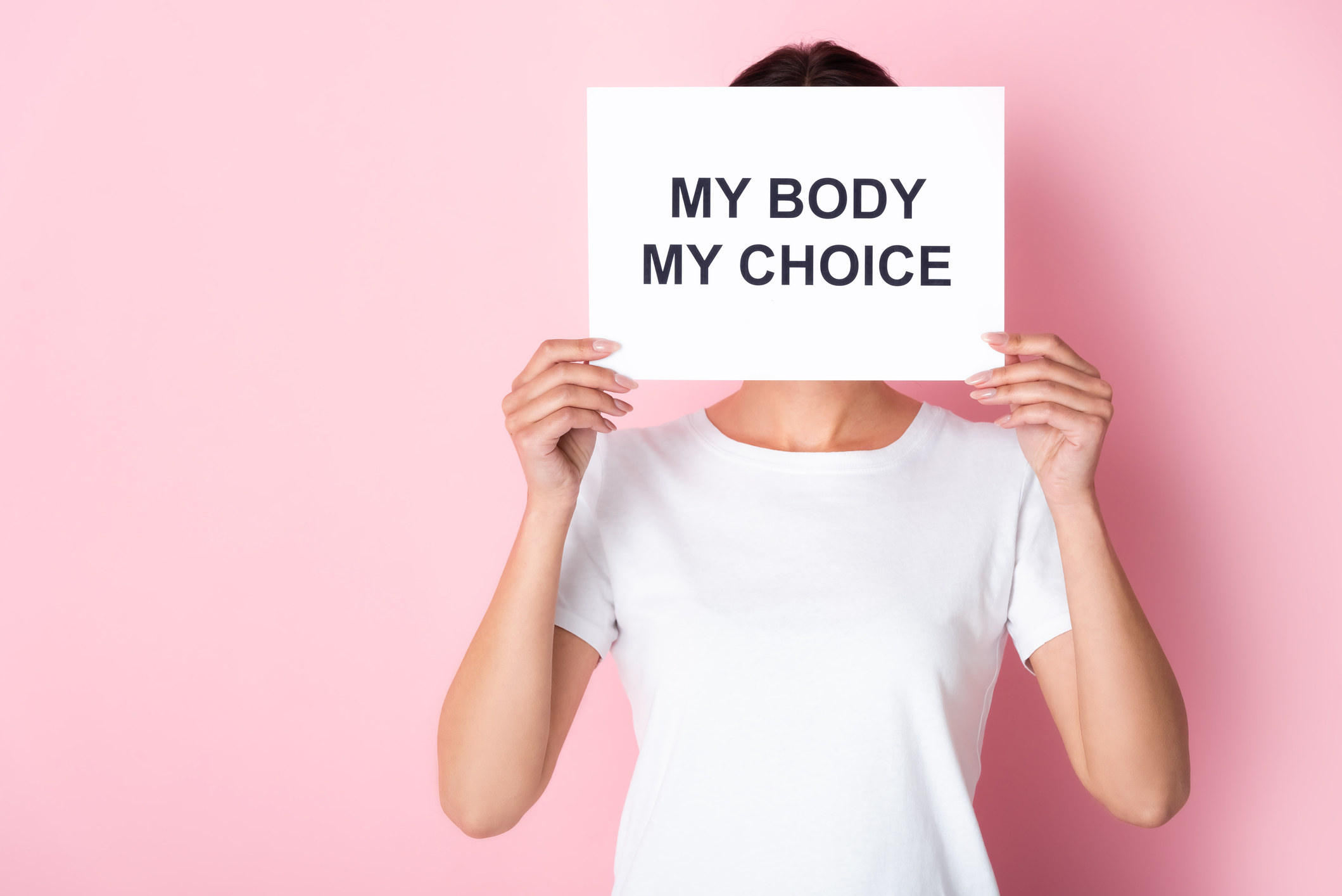 A woman holding a sign in front of her face reading &quot;My body, my choice&quot;