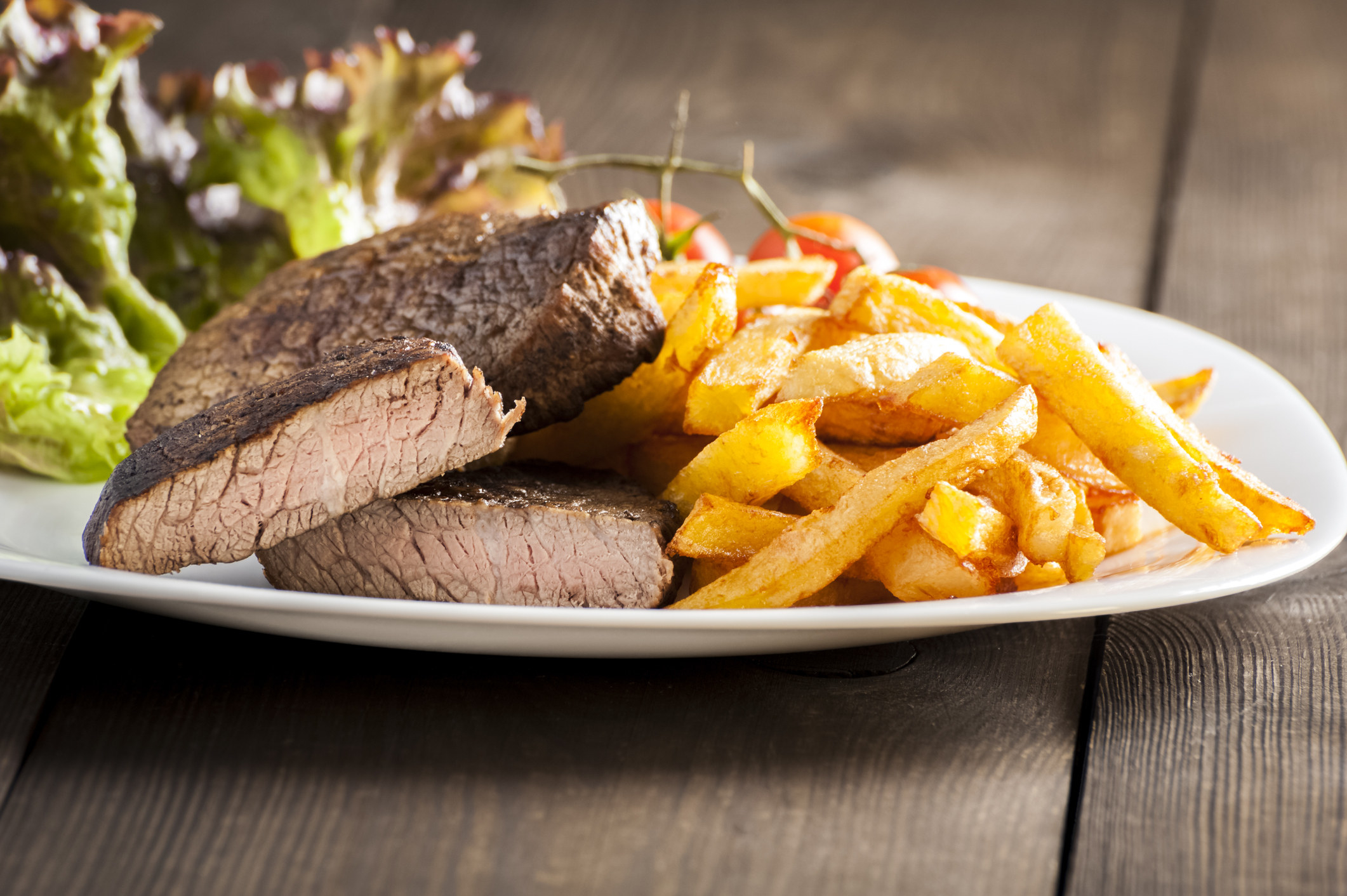 a well done cooked steak on a plate with fries