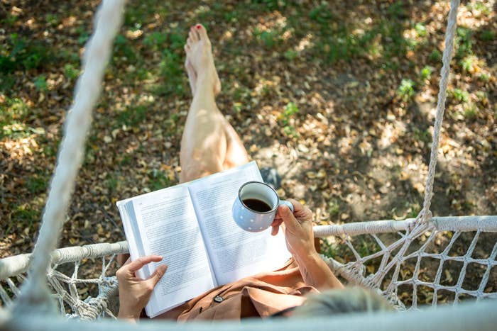A woman reading outside with a cup of coffee.