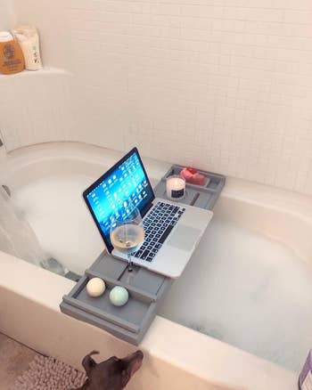reviewer's bath caddy with a laptop wine and candle on it