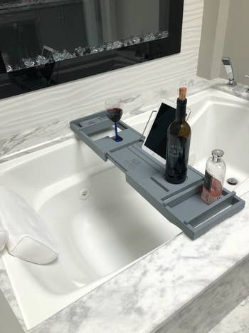 bath caddy with a wine bottle and accessories on it