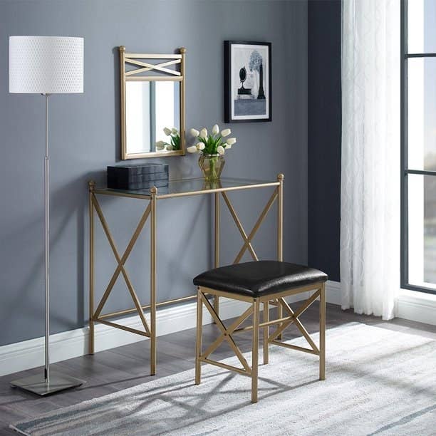 An image of a three-piece gold metal vanity set that includes one stool, one vanity, and one mirror