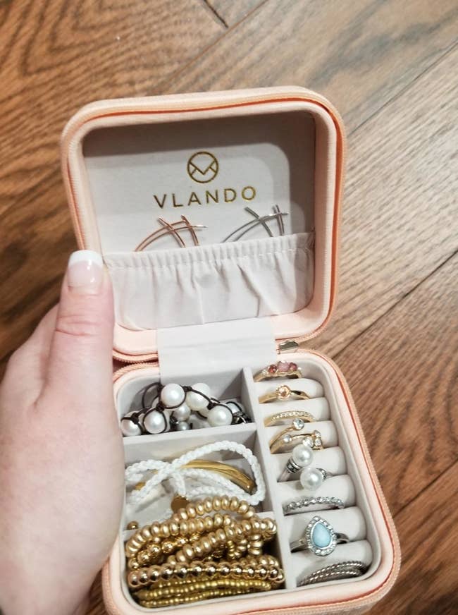 reviewer showing their travel jewelry case loaded with lots of bracelets and rings
