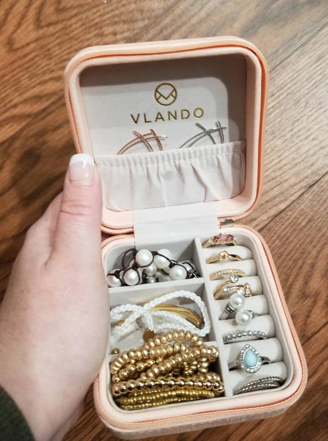 reviewer showing their travel jewelry case loaded with lots of bracelets and rings