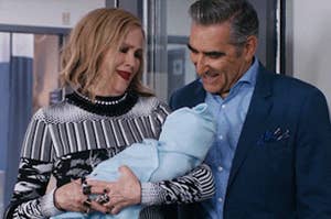 moira and johnny from schitt's creek holding a baby