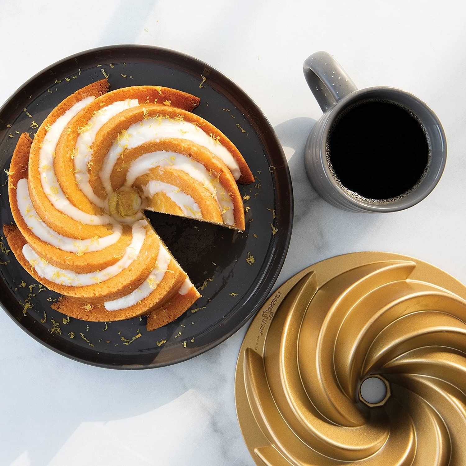 overhead shot of a bundt cake next to the gold bundt pan and a mug of coffee