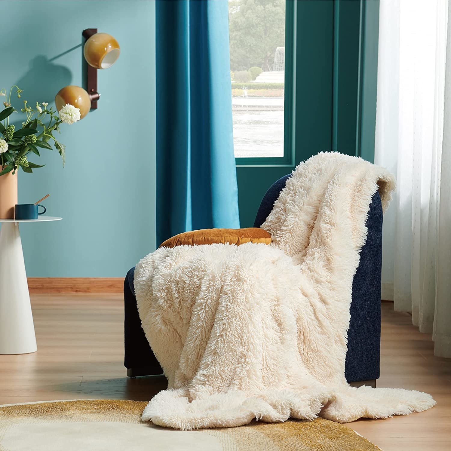 white faux fur blanket draped over a white accent chair
