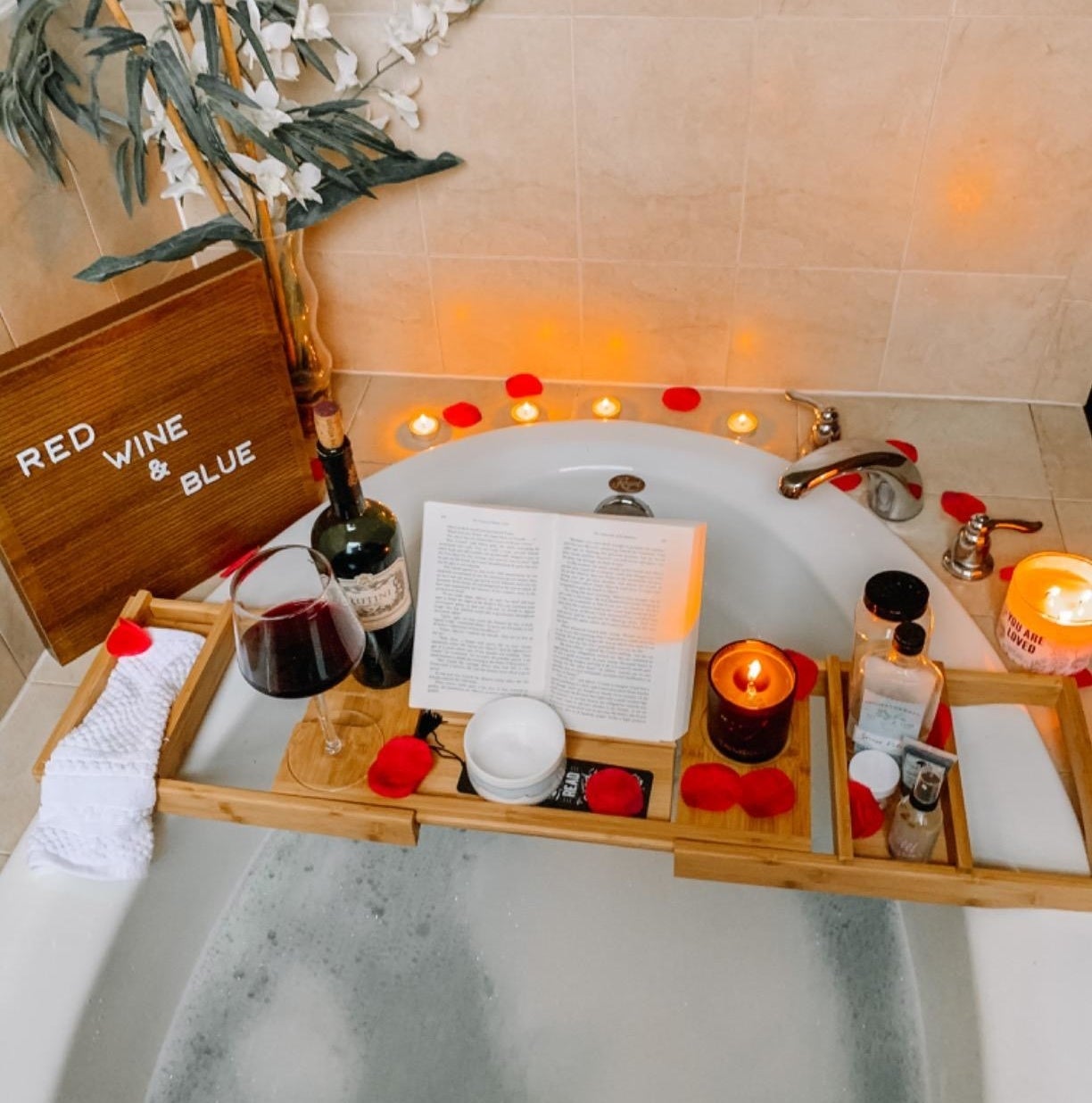 Reviewer image of a wooden bath caddy holding an book, wine glass, wine bottle, candle, and more accessories