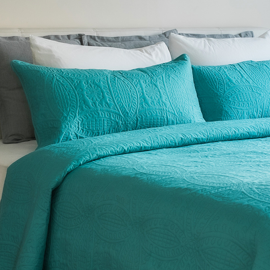 An image of a ocean teal three-piece quilt set with a coverlet and two coordinating shams