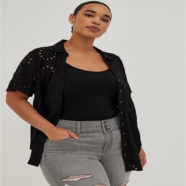 Model wearing a black layered top and gray jeans