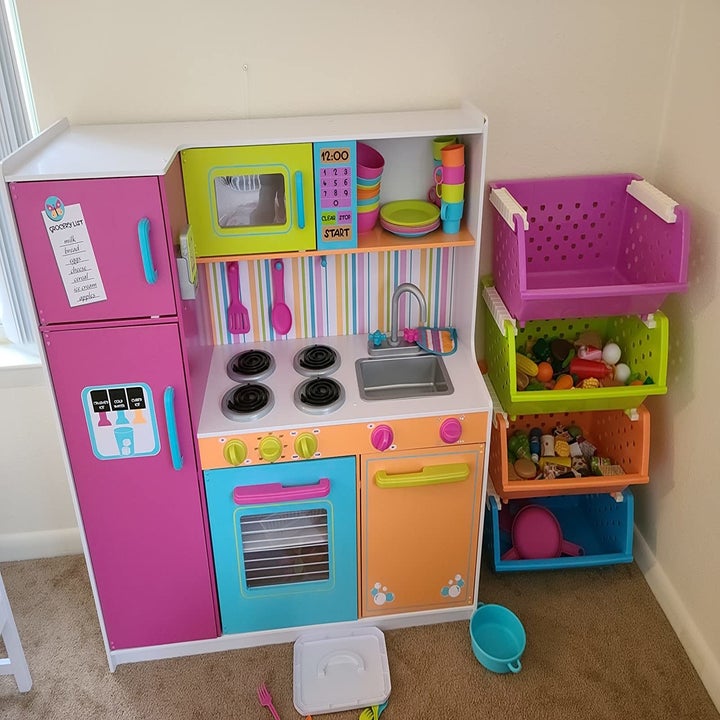 Reviewer's photo showing the organizer holding toys near a play kitchen