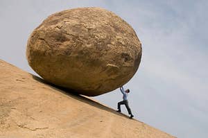 a man holding up a giant boulder 