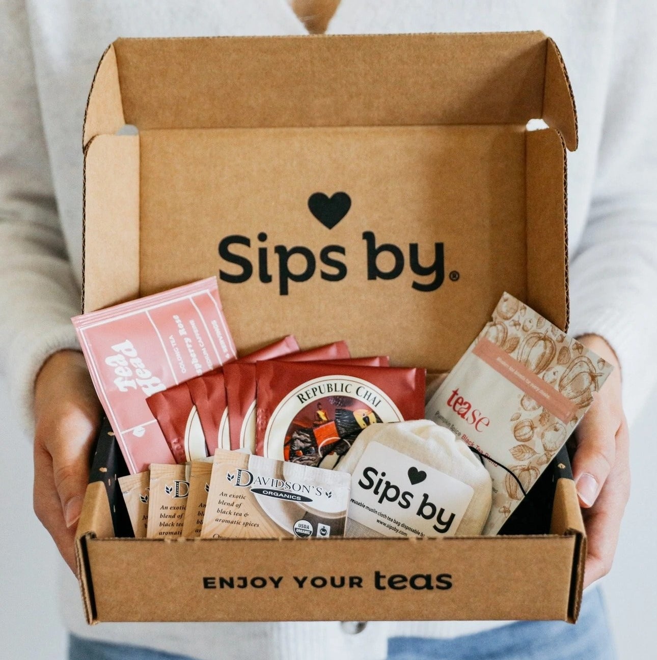 a model holding an open Sips by box filled with different tea bags
