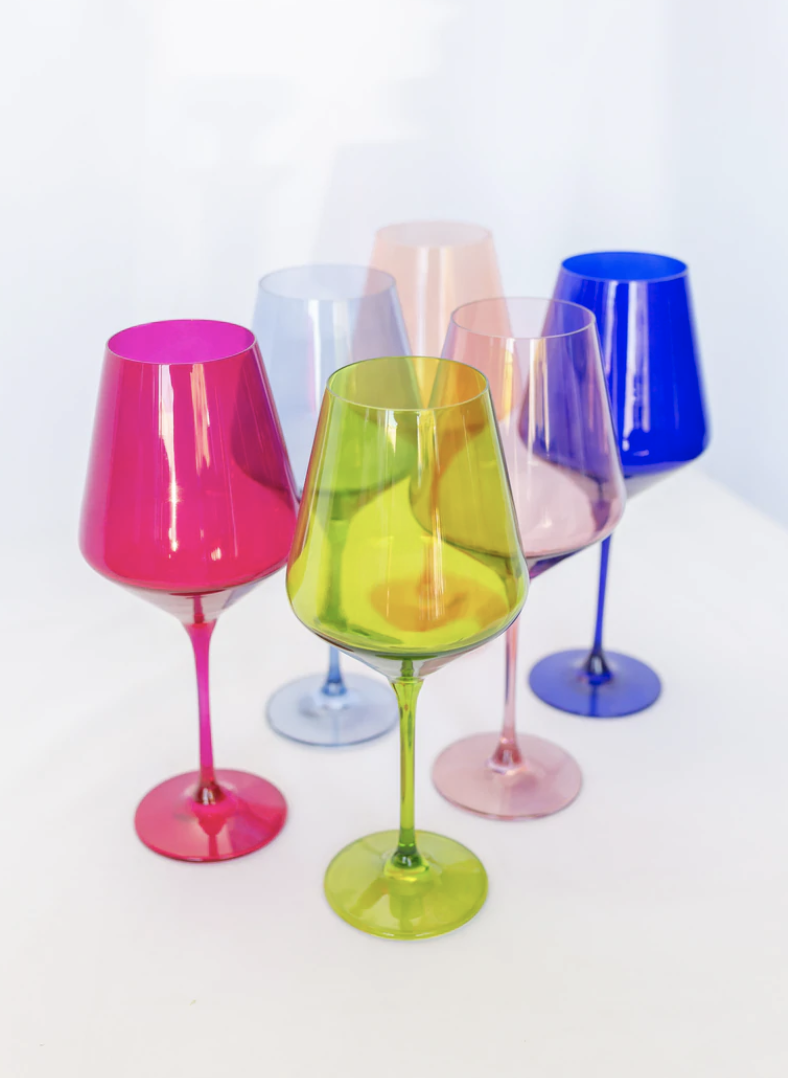 Six colored wine glasses on white table