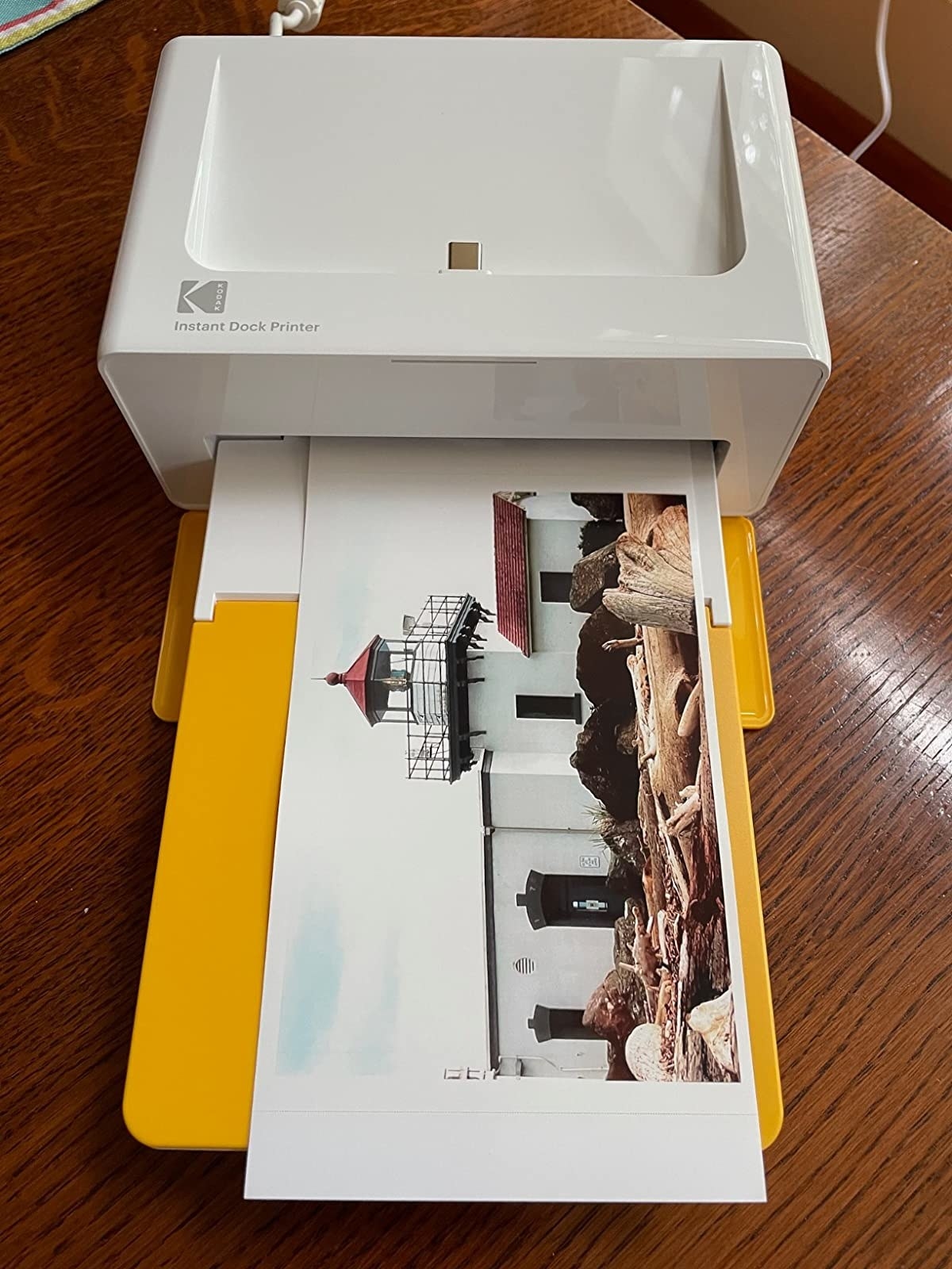 a reviewer photo of the printer with a printed photo in the tray