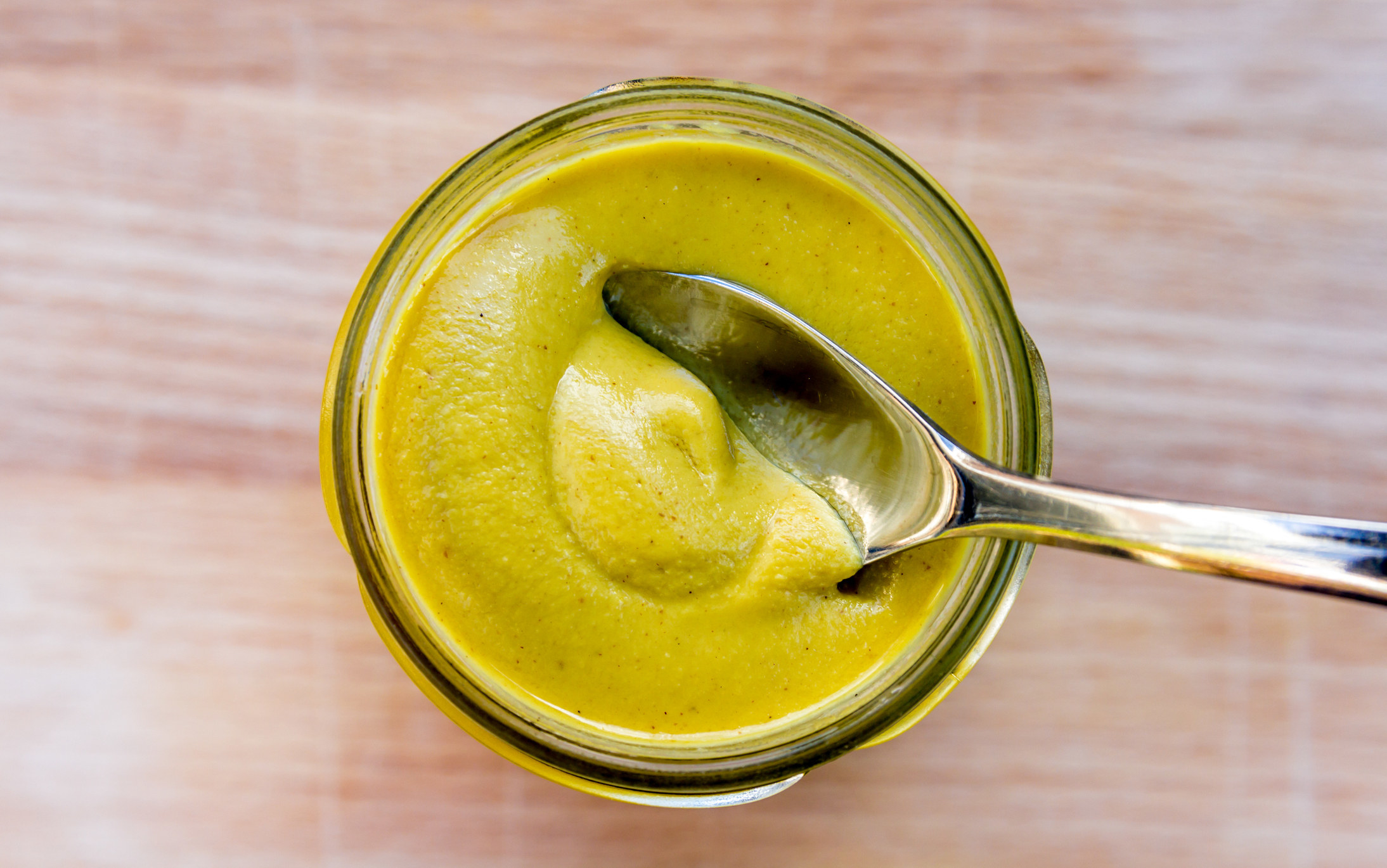 A spoon in a jar of mustard.