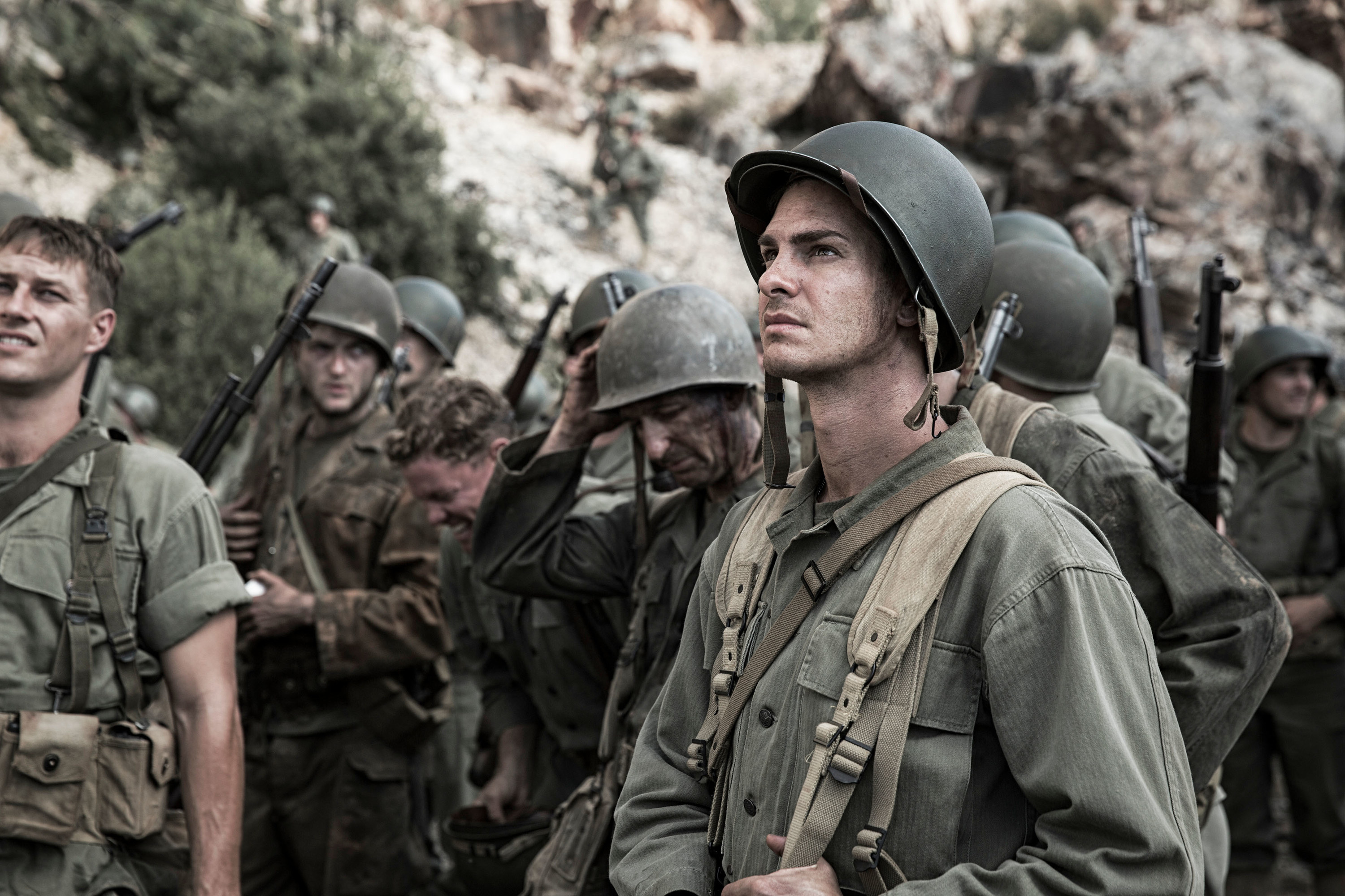 Andrew Garfield stands among a bunch of soldiers