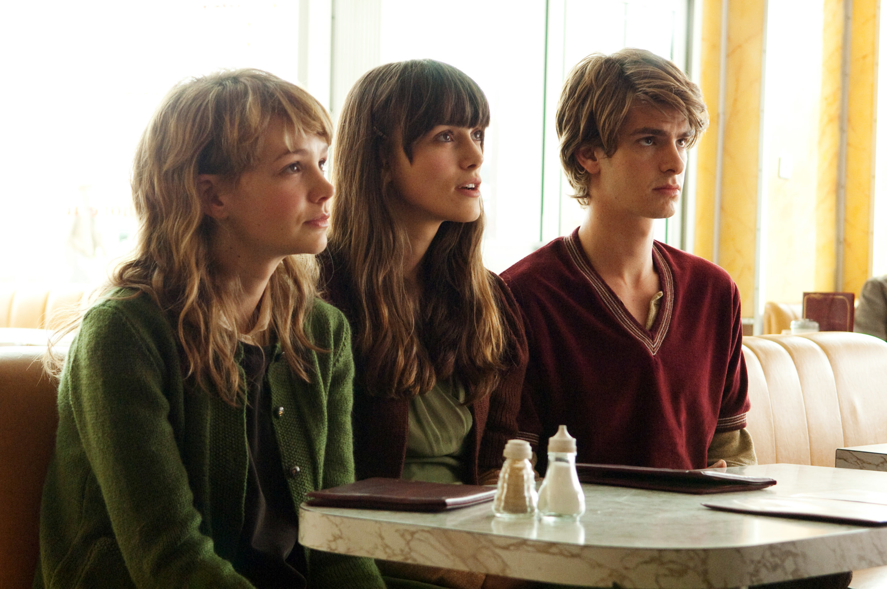 Carey Mulligan, Keira Knightley, and Andrew Garfield sit in a booth together