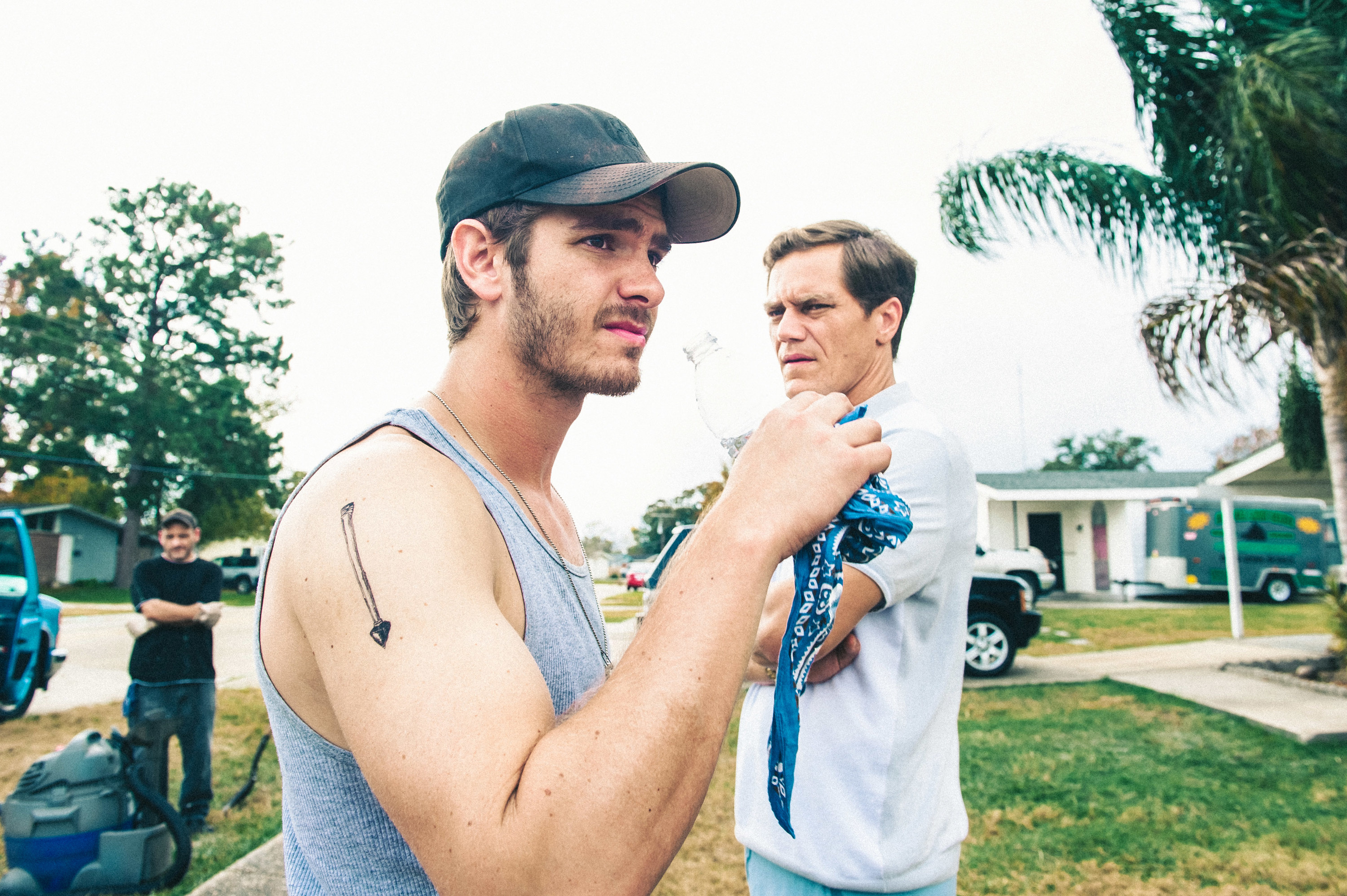 Andrew Garfield and Michael Shannon stand in a yard