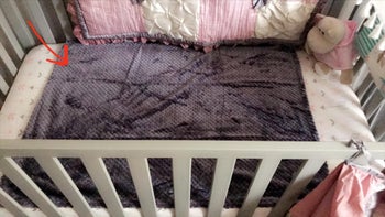Reviewer image of gray blanket spread out inside crib
