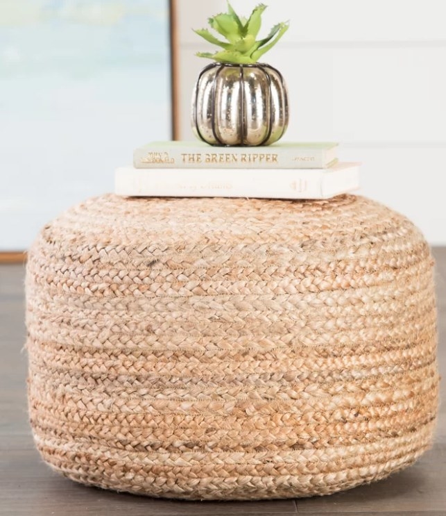 Jute pouf with books and a plant sitting on top.