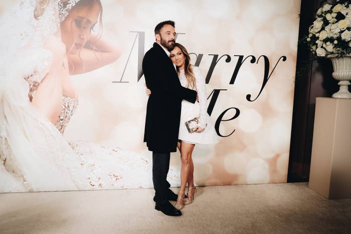 Ben embraces Jennifer in front of a Marry Me poster