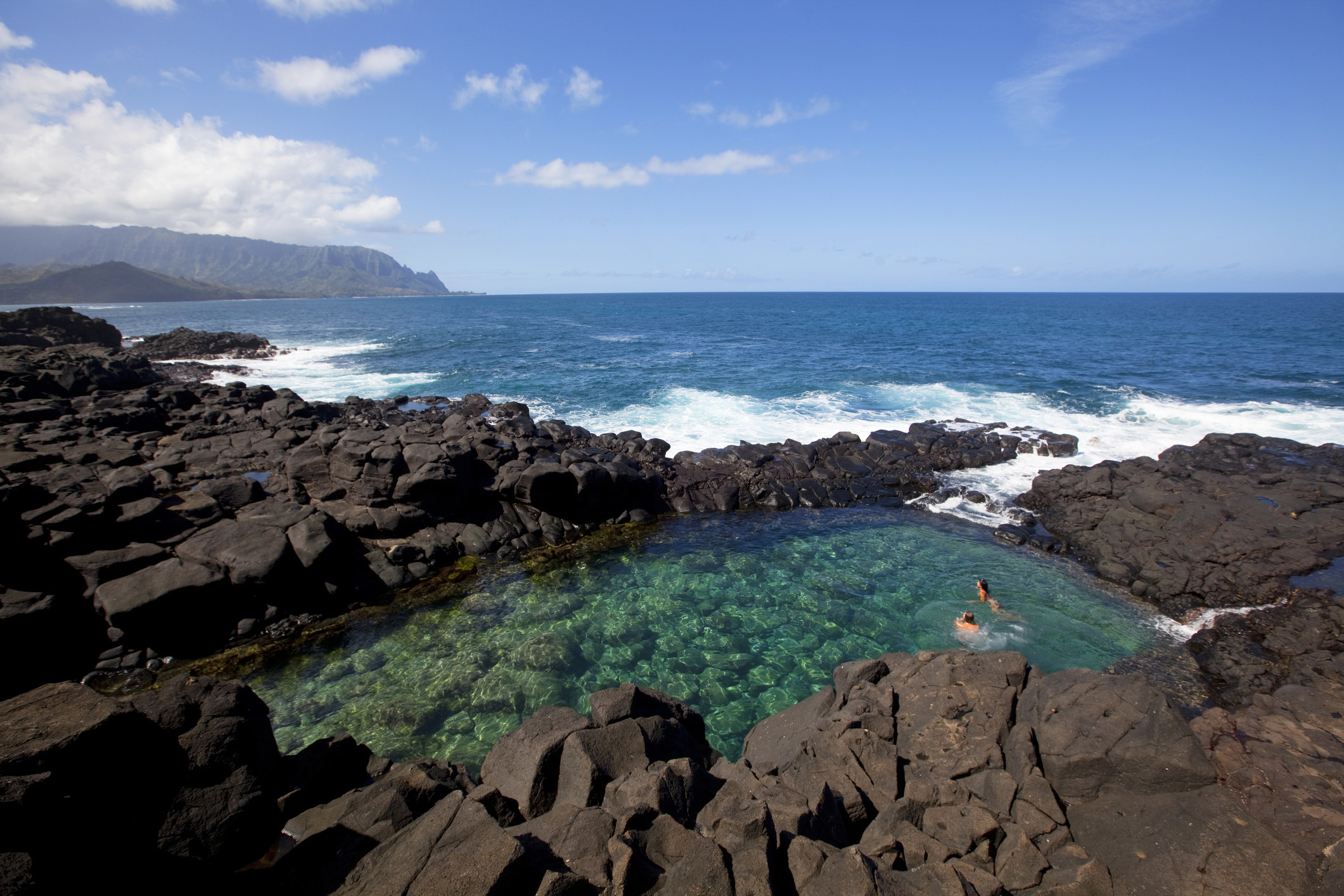 A tidepool in Hawaii surrounded by ocean.