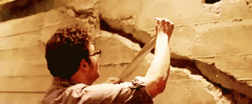Seth Rogen putting duct tape over a giant crack in a concrete wall in This Is The End