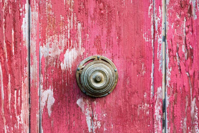A close-up of a red door with a knob in the center, similar to those seen in the Shire