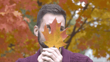 Man sarcastically holding a fall leaf to his face and then slowly pulling it down