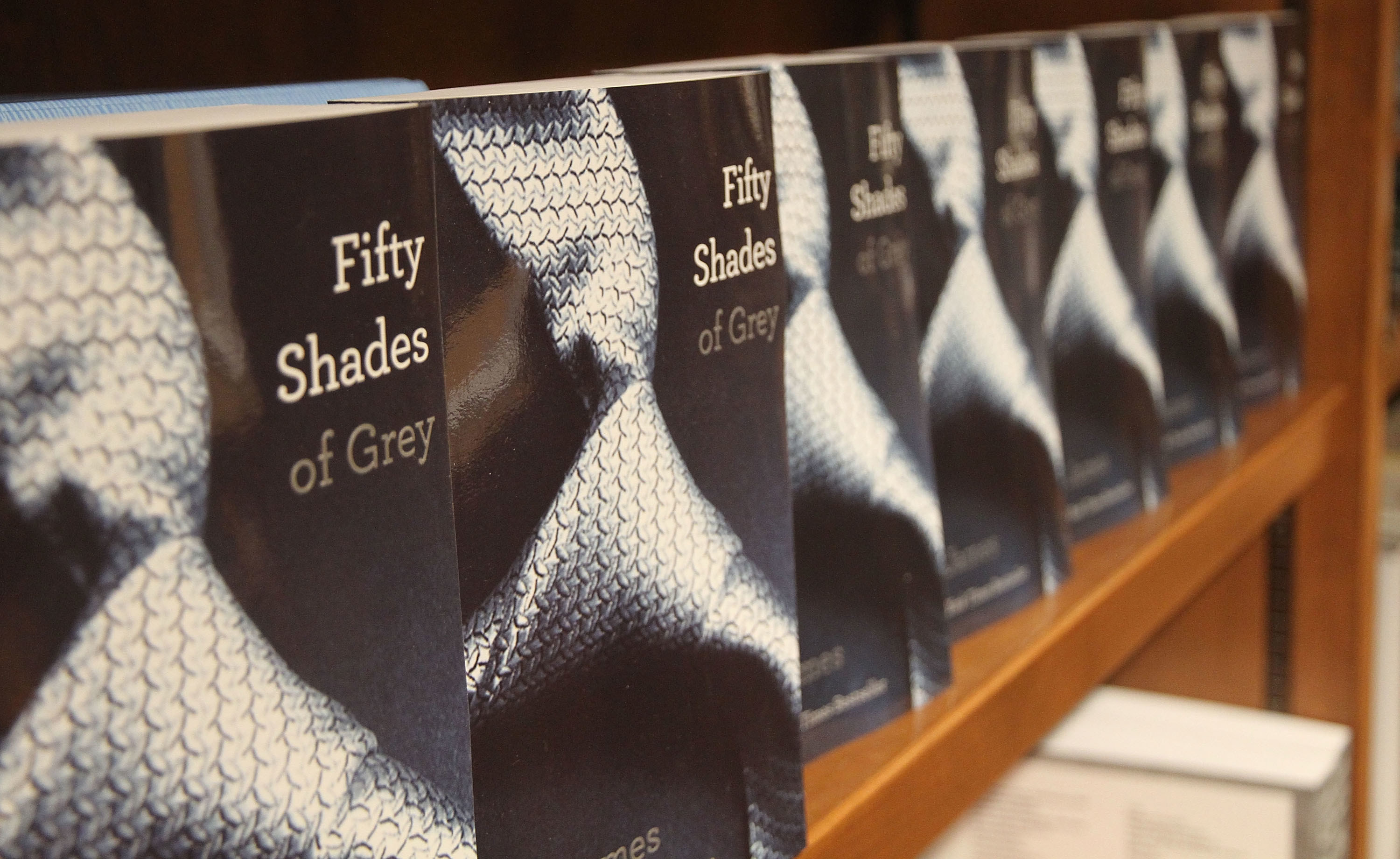 Several copies of the book Fifty Shades of Grey on a shelf