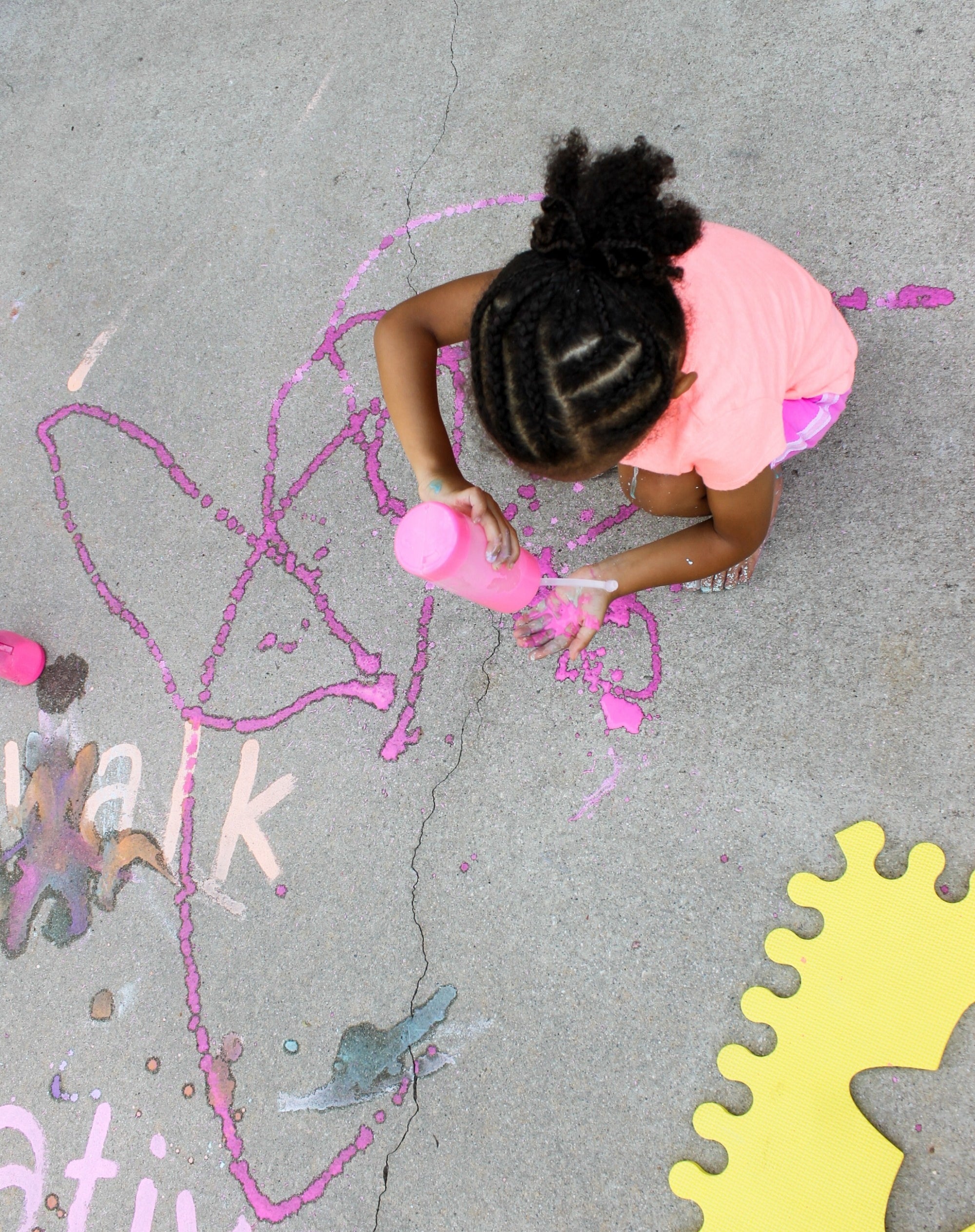 blogger&#x27;s photo of a child pouring chalk paint on the sidewalk with a squeeze bottle