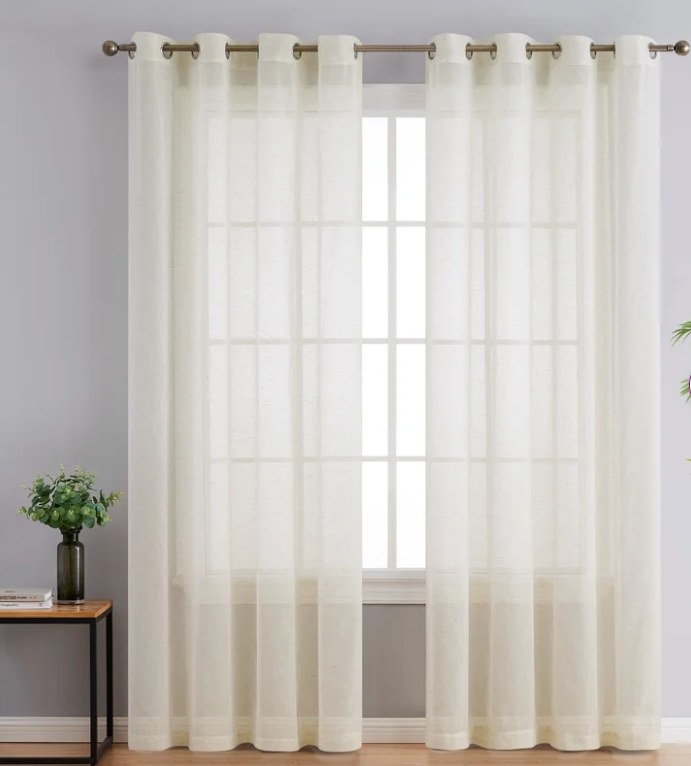 Linen colored semi-sheer drapes hung on large window.